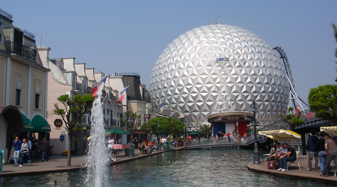 A futuristic globe sits at the end of a man-made lake at a theme park